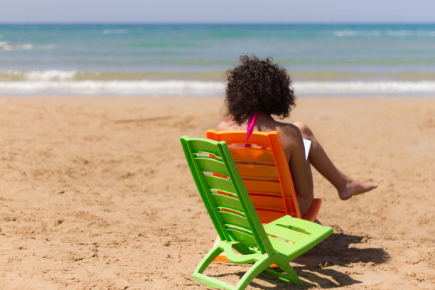 女人日光浴:宁静的海滩，大海，海浪，沙子;充满活力的颜色图片下载