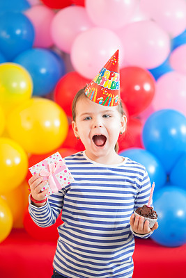 三岁女孩戴着派对帽庆祝生日快乐图片下载