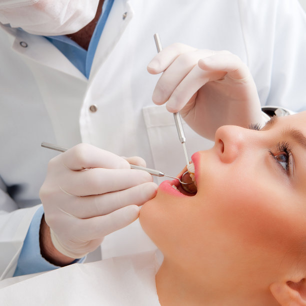 牙医拿着牙科器械在年轻女子的嘴里图片下载