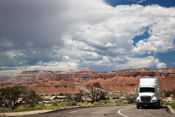 犹他州沙漠公路上，一辆白色卡车在威胁的天空下行驶图片下载
