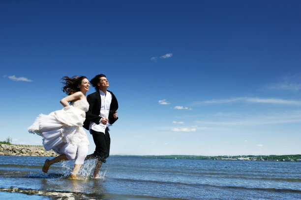 一对年轻夫妇在海滩上跑步图片下载