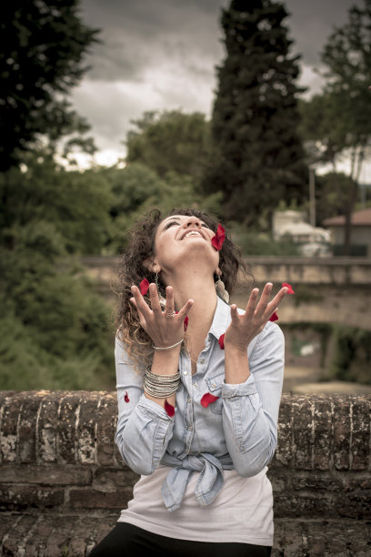 红花瓣下的年轻快乐女子图片下载