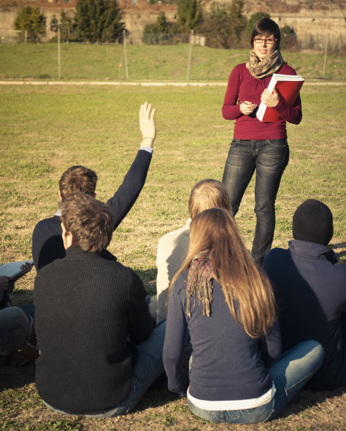老师在草坪上为她的学生朗读图片下载