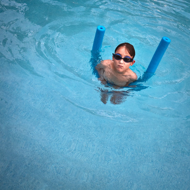 一个戴着深色护目镜的小孩在游泳池里图片下载