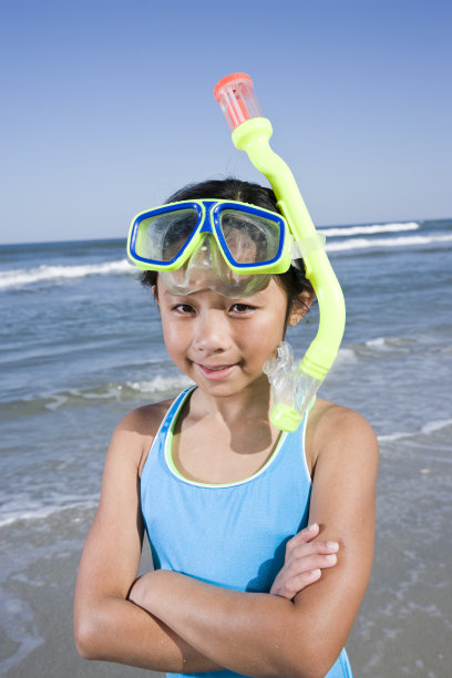 快乐的亚洲女孩戴着面具和通气管在海滩上图片下载