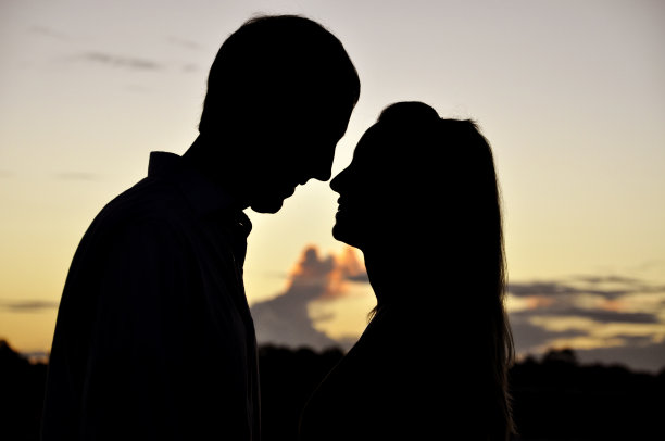 年轻的剪影夫妇在晨光图片下载