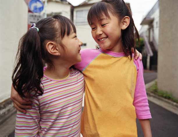 两个女孩(6尺9寸)手挽着手走着，面带微笑图片下载