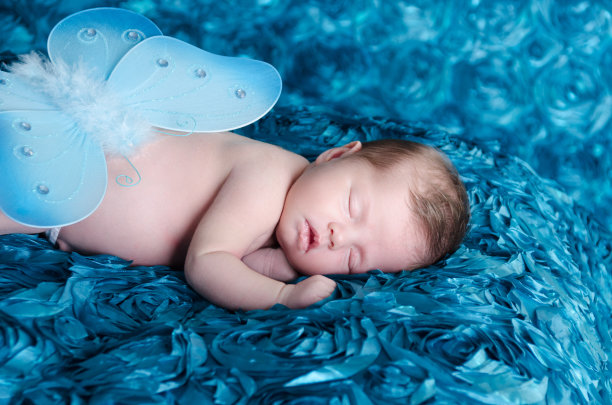 刚出生的小女孩用蝴蝶盖着尿布。素材图片