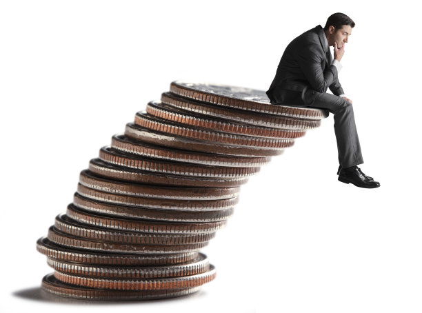 商人坐在倾斜的一堆硬币上图片下载