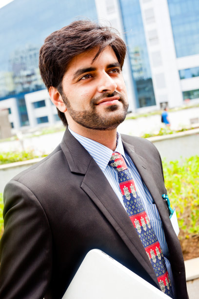 年轻的亚洲印度商人与笔记本电脑户外肖像图片下载