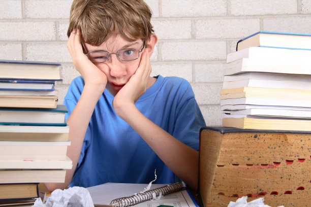 小男孩因成堆的书而沮丧图片下载