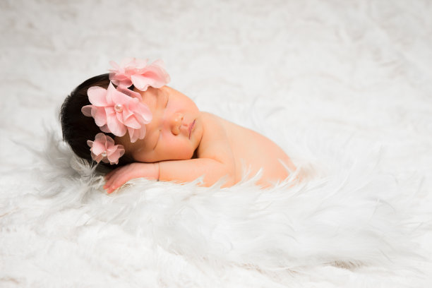新生的女婴躺在羽毛花环中素材图片