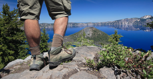 俯瞰火山口湖的徒步旅行者的腿和靴子图片下载