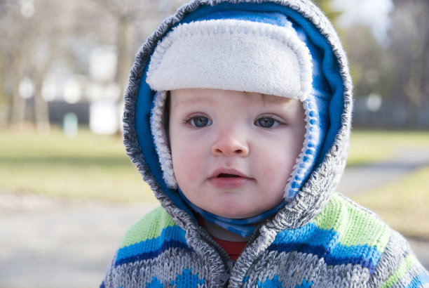 一个一岁的男孩为寒冷的天气穿好衣服。图片下载