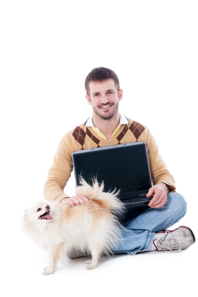 手持手提电脑的男子宠物狗波美拉尼亚的图片下载