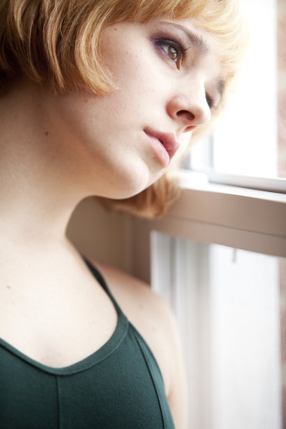 悲伤的年轻女子向窗外望去图片下载