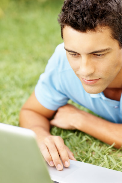 一个随意的人在草地上用笔记本电脑的特写图片下载