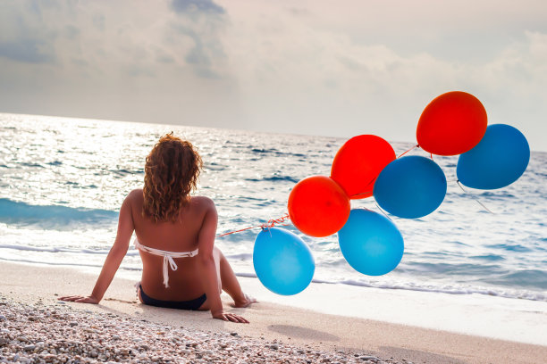 在海滩上拿着气球的女人图片下载