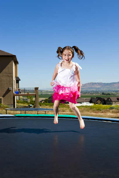 可爱的小女孩在蹦床上跳图片下载