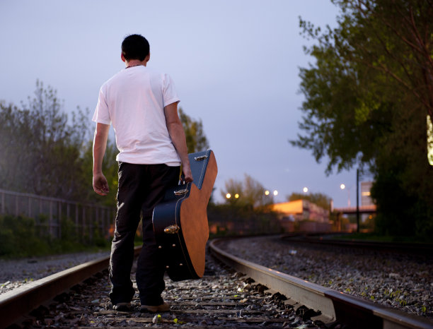 黄昏时在铁路上散步的音乐家图片下载