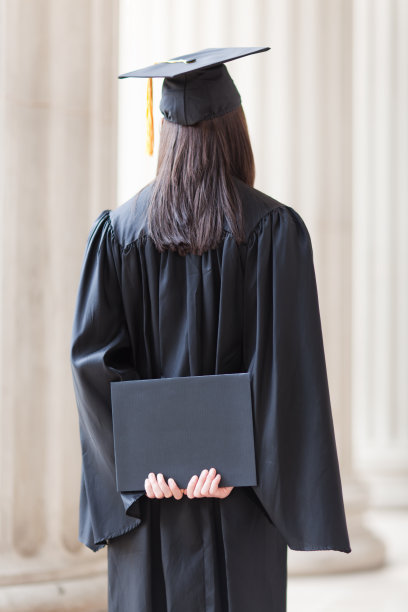 女学生背后穿着毕业礼服，抓着文凭背后图片下载