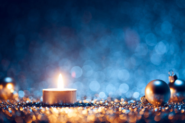 一根两边有圣诞球的点燃的蜡烛图片下载