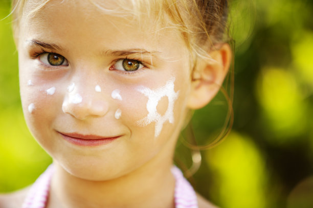 女孩用防晒霜涂抹在她的脸颊上，以太阳的形状图片下载