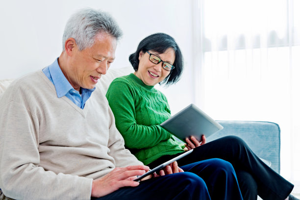 快乐的亚洲老年夫妇在数字平板电脑上阅读素材图片