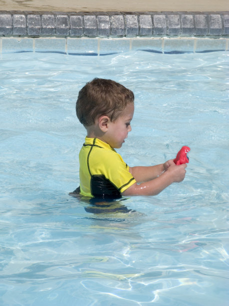 幼童在游泳池玩塑料玩具砖边图片下载