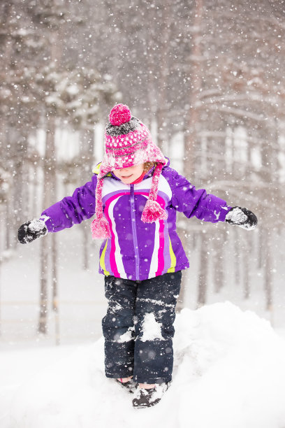 穿紫色夹克的女孩在冬天的雪中玩耍图片下载