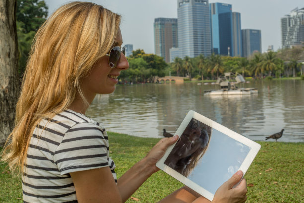 在城市公园里使用数位平板电脑的年轻女人图片下载