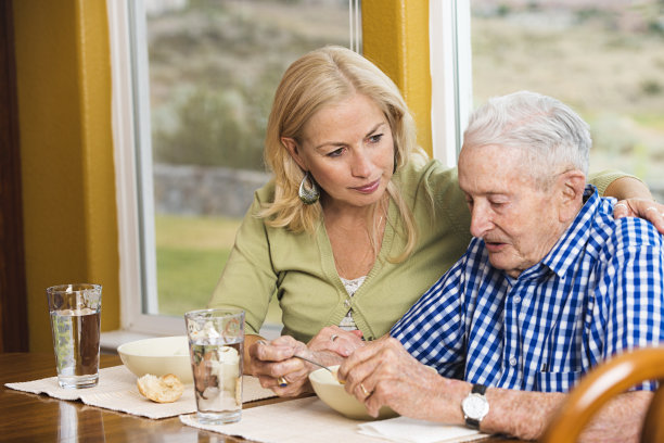 有爱心的成年女儿看着她的父亲喝汤图片下载