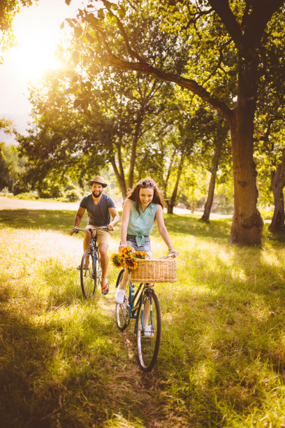 一对情侣在一个阳光明媚的夏日里在公园里骑自行车图片下载