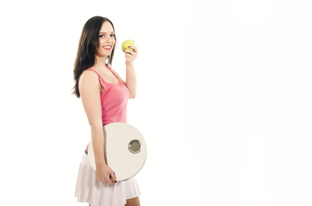美丽的年轻女子拿着测量仪器，吃着苹果图片下载