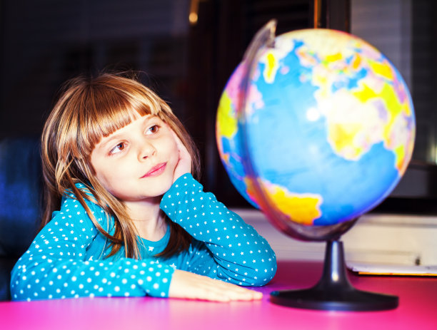 小女孩拿着地球仪坐在办公桌前图片下载