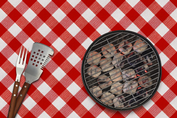 在野餐桌布上放置发光的煤球和烧烤用具图片下载