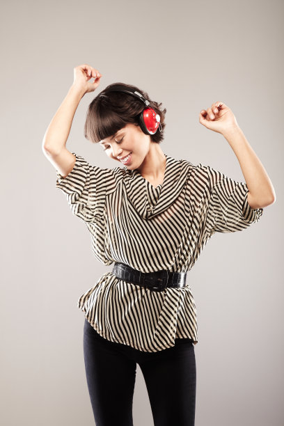 美丽的黑发女子跳舞和听音乐耳机图片下载