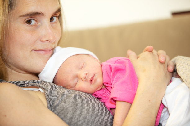 一个女人抱着她熟睡的8天大的女儿。图片下载