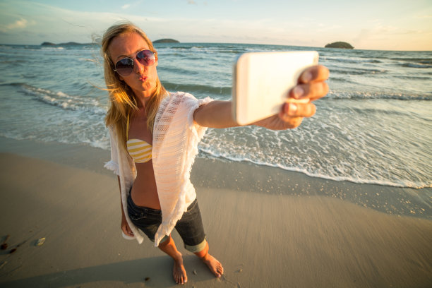 日落时在海滩上自拍的时尚女孩图片下载