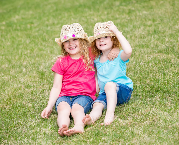 两姐妹坐在草地上，手挽着手图片下载