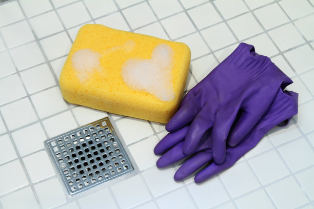 浴室地砖上放海绵和橡胶手套图片下载