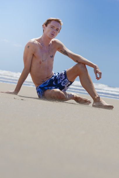 在多风的海滩上晒太阳的金发男人图片下载