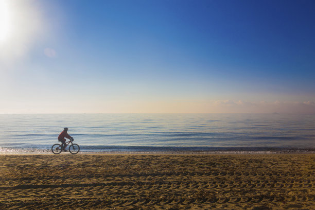 沿着海滩骑自行车的女人图片下载
