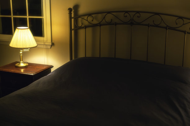 照亮床侧灯在黑暗的晚上卧室图片下载