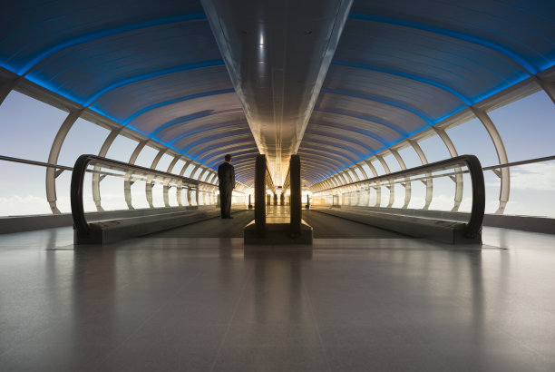 商人在移动的人行道上朝着明亮的阳光走去图片下载