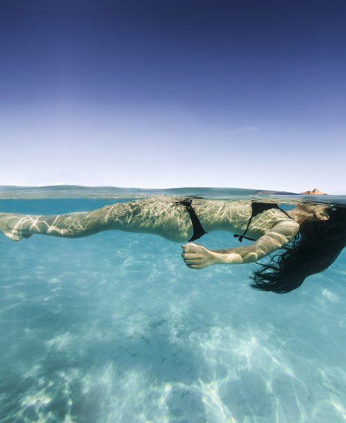 年轻女子漂浮在博拉博拉清澈的海图片下载