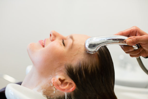 美发师正在冲洗年轻女子的头发图片下载