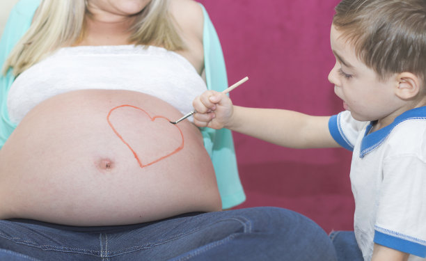 小男孩在妈妈肚子上画心形图片下载