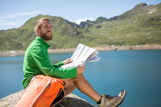 年轻的徒步旅行者坐在岩石上，在地图上寻找小路图片下载