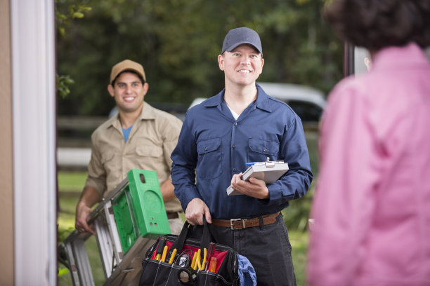 服务行业:两名多民族修理工站在客户家门口。素材图片